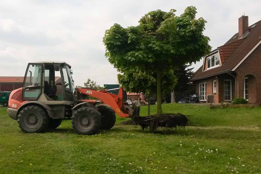 Ein Traktor steht auf einer Wiese vor einem Haus.