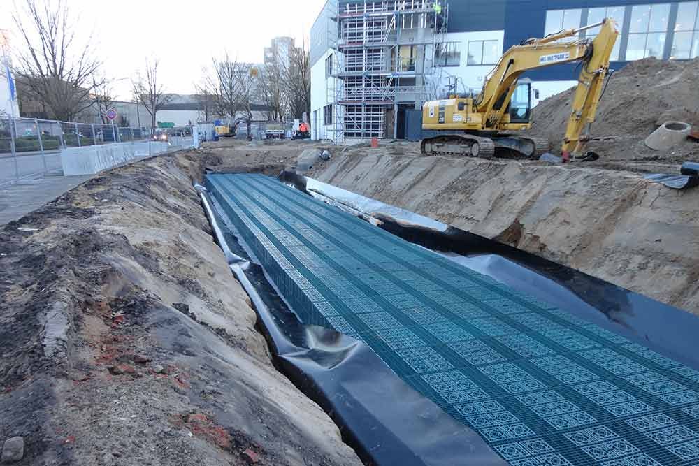 Eine Baustelle mit einem gelben Bagger und einem großen Gebäude im Hintergrund.