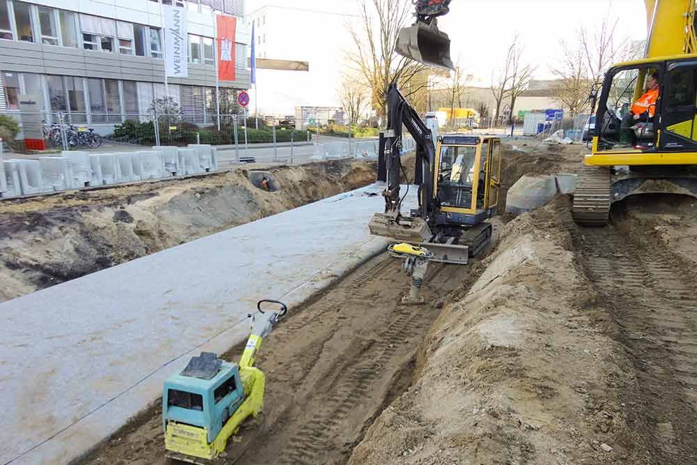 Eine Baustelle mit einem gelben Bagger und einem blauen LKW.