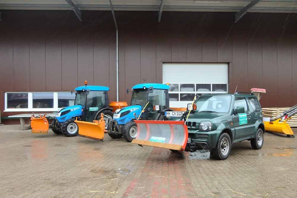 Vor einem Gebäude steht eine Reihe Schneepflüge.