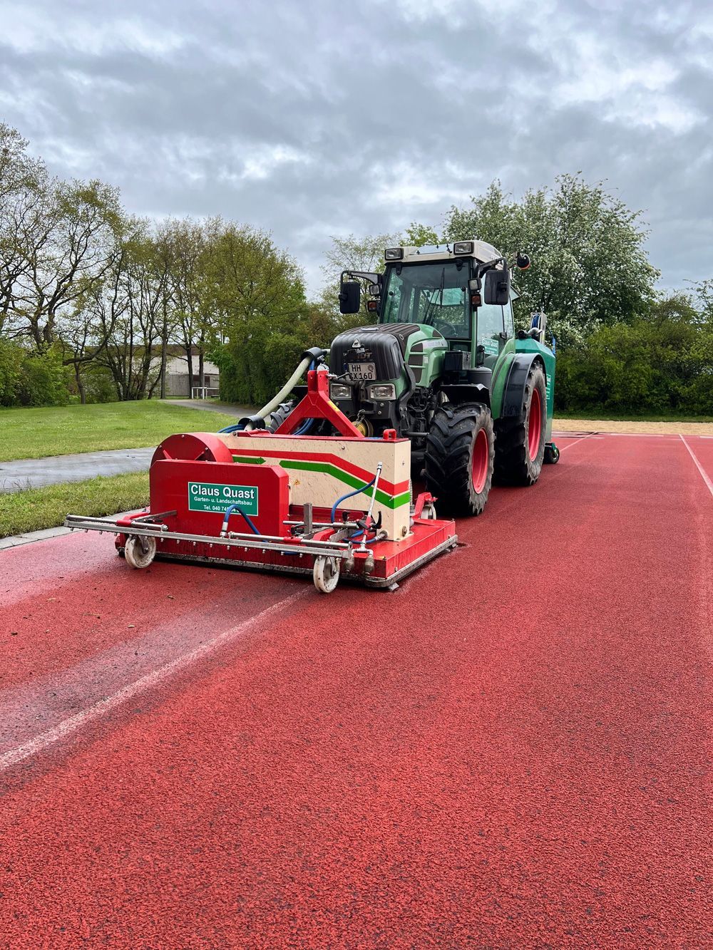 Ein Traktor fährt auf einem Weg neben einer Maschine her.