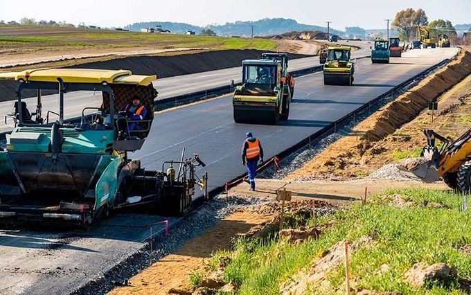 Un grupo de trabajadores de la construcción está colocando asfalto en una carretera.