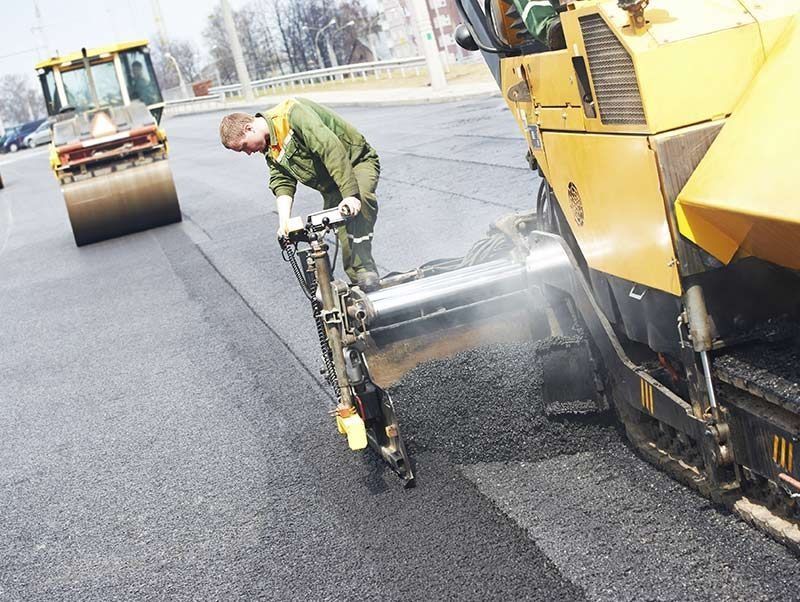 Un hombre está trabajando en una carretera con una máquina.