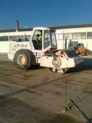 Un rodillo blanco está estacionado en un estacionamiento frente a un edificio.