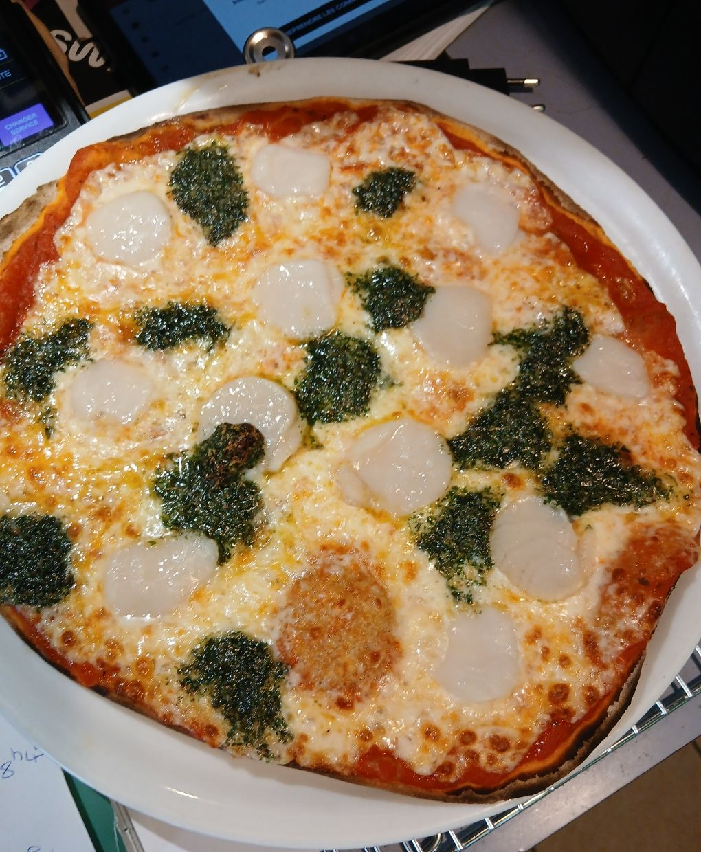 Une personne mange une part de pizza à une table, accompagnée d'une salade et d'une bière.