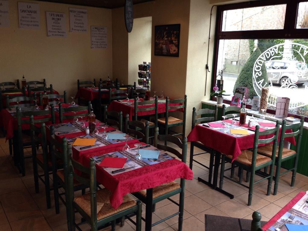 Intérieur d'un restaurant avec nappes rouges, tables dressées et chaises.