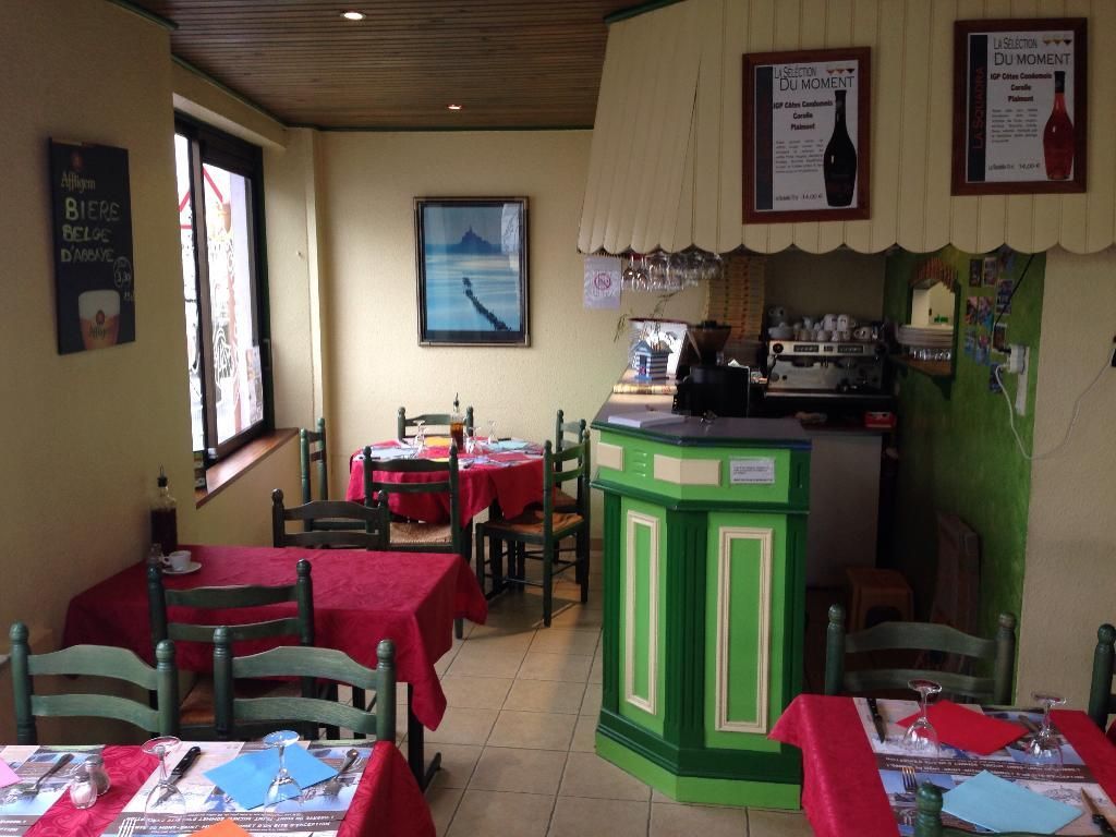 Intérieur d'un petit restaurant avec nappes rouges, chaises vertes et bar vert.