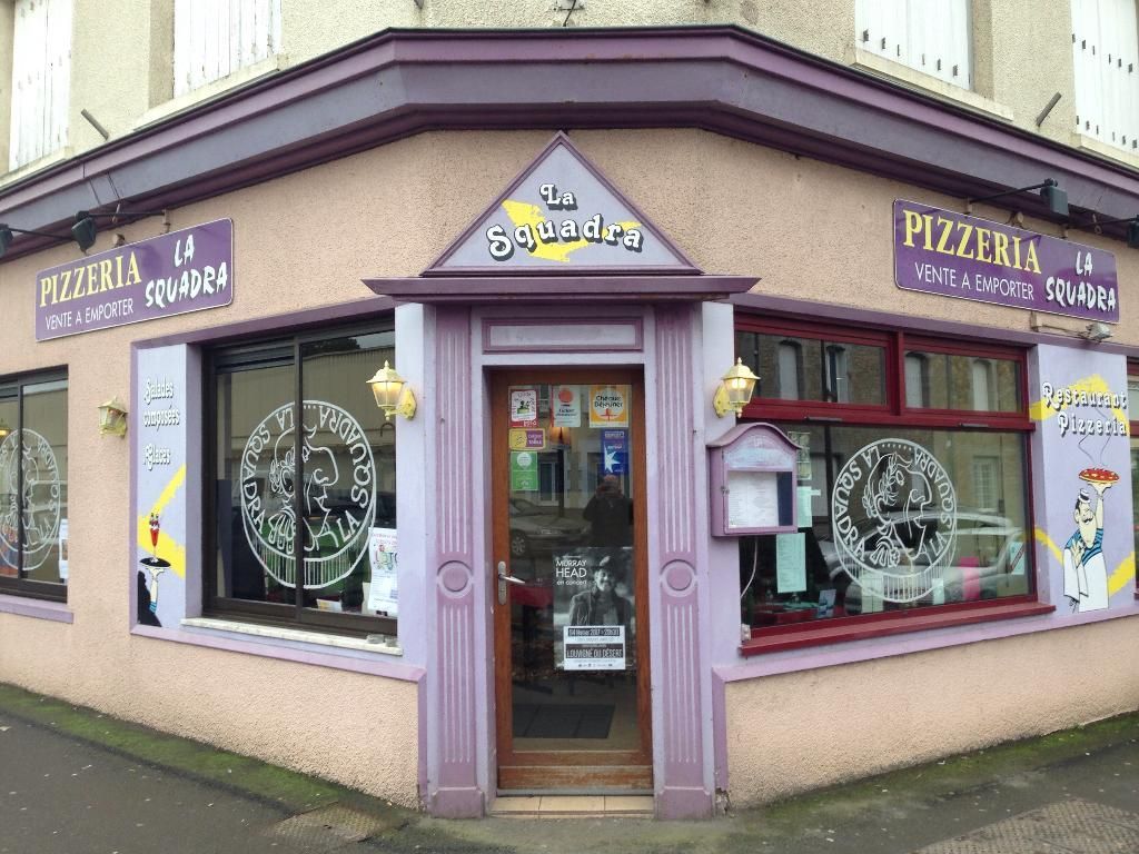 Pizzeria « La Bombasta », bâtiment d'angle avec des finitions et une enseigne violettes.