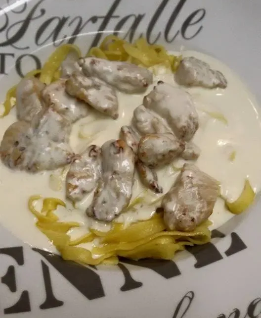 Plat de poulet et pâtes à la sauce crémeuse, présenté sur une assiette décorative.