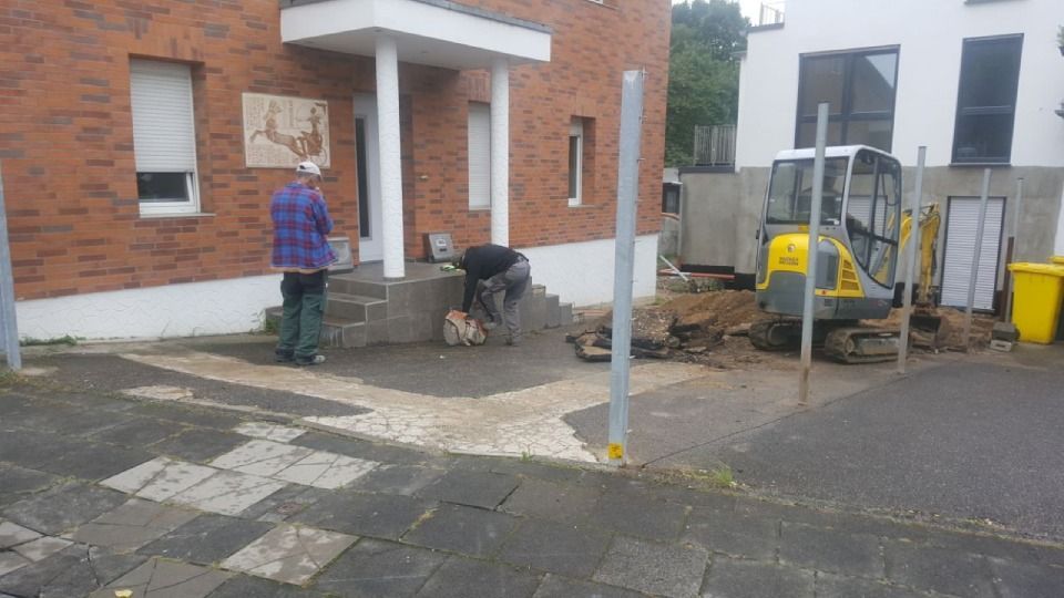 Ein Mann im karierten Hemd steht vor einem Backsteingebäude, Metallbau & Garten- & Landschaftsbau Ökmen