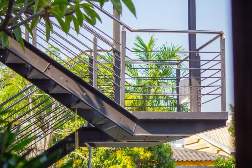 Eine Metalltreppe mit einem Geländer aus Edelstahl ist von Bäumen umgeben. Metallbau & Garten- & Landschaftsbau Ökmen