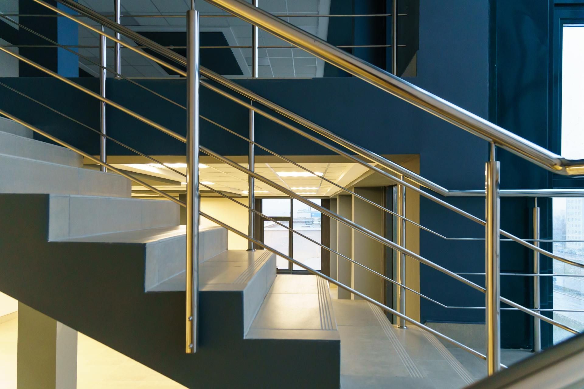 Eine Treppe mit einem Metallgeländer und der Spiegelung eines Gebäudes, Metallbau & Garten- & Landschaftsbau Ökmen