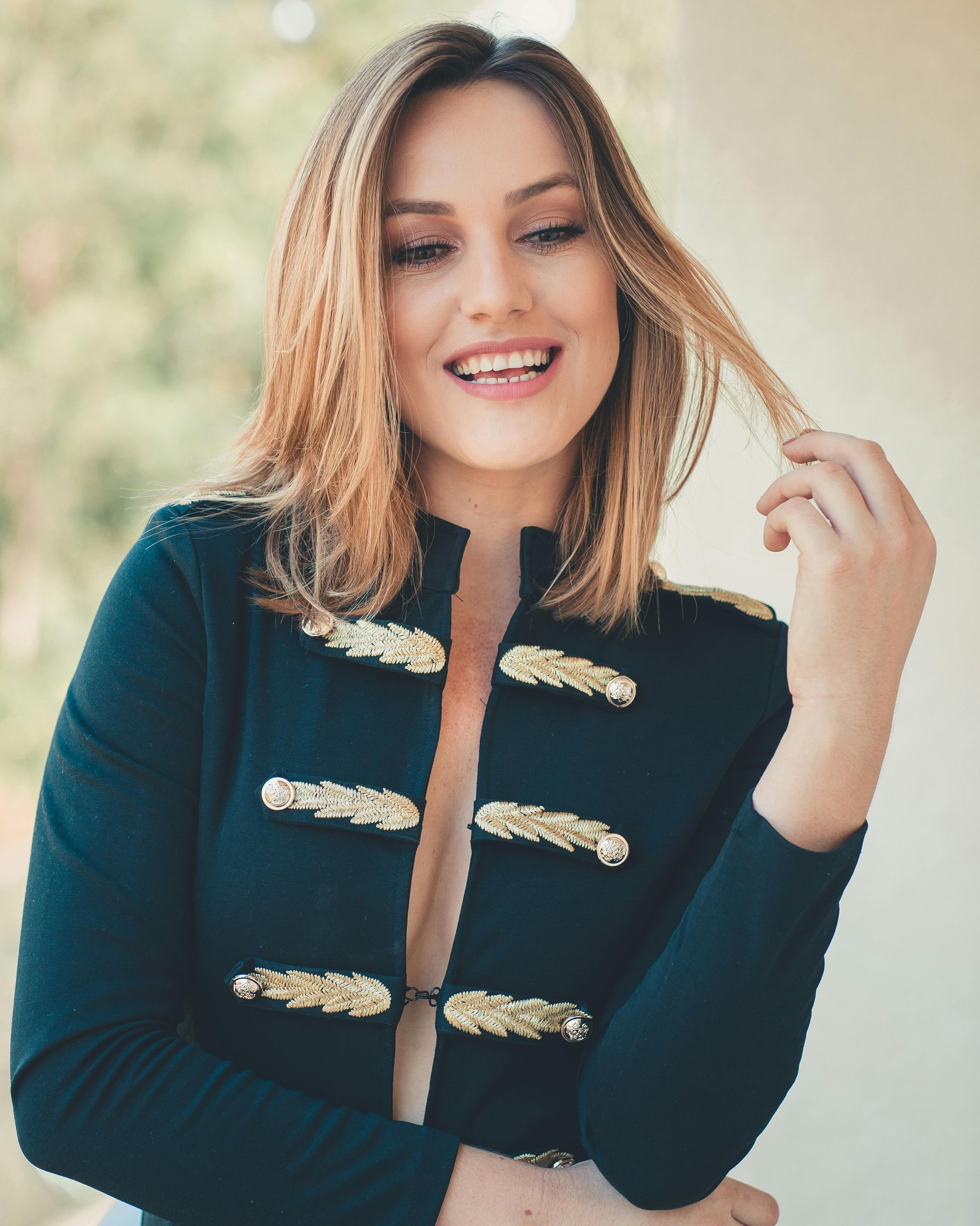 Una donna con una giacca nera sorride e si tiene i capelli
