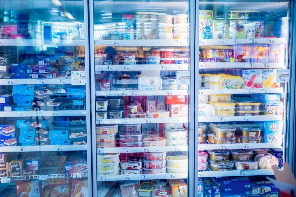 Tres vitrinas refrigeradas para comestibles, surtidas con diversos productos lácteos, tarrinas y alimentos envasados.