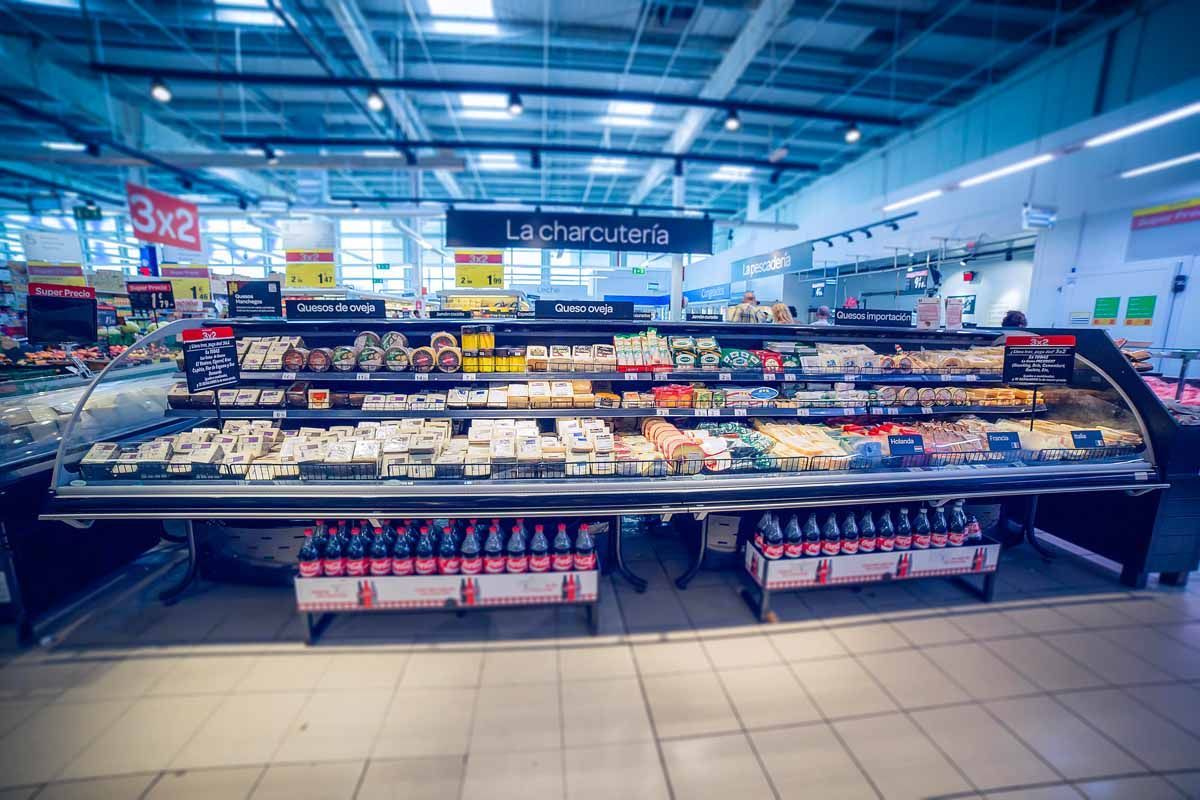 Una vitrina refrigerada llena de productos lácteos envasados ​​en un pasillo de supermercado muy iluminado.