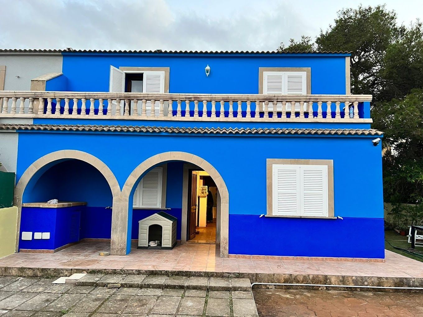 Una casa azul con una caseta para perro delante.