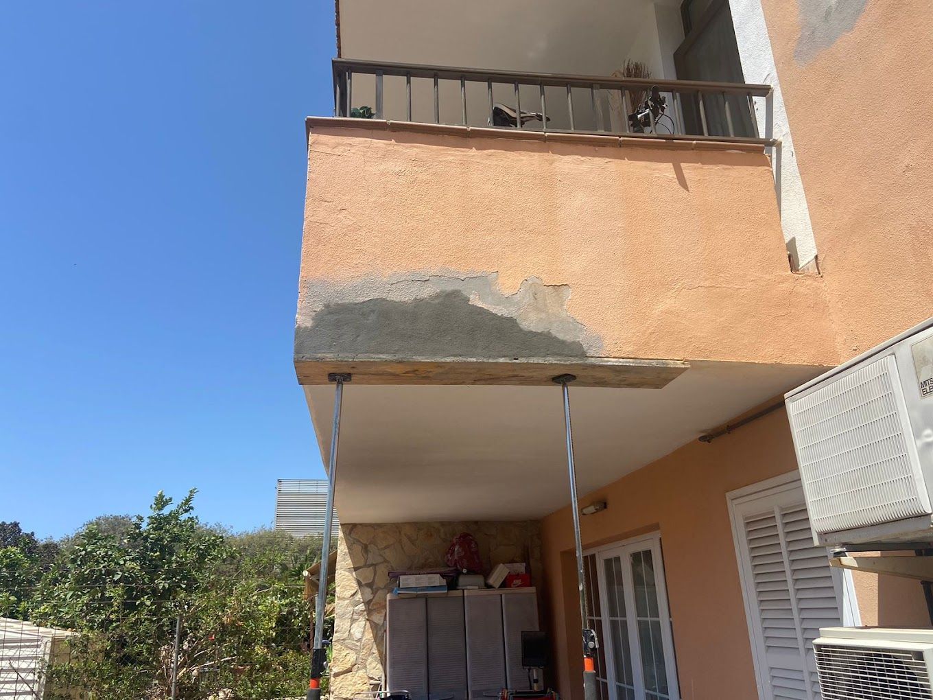 Un balcón en el costado de un edificio con un cielo azul al fondo.