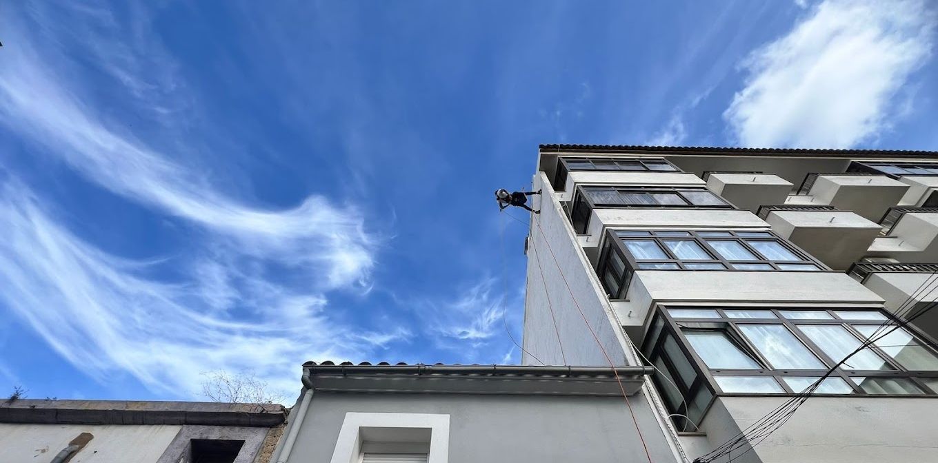 Un edificio con muchas ventanas contra un cielo azul con nubes.