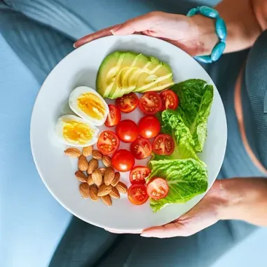 Una mujer sostiene un plato de comida saludable en sus manos.