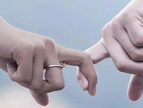 Un hombre y una mujer se toman de la mano con un anillo en el dedo.