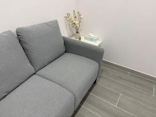 Un sofá gris está sentado en una habitación al lado de una mesa pequeña.