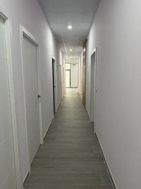 Un pasillo largo con muchas puertas y una ventana.