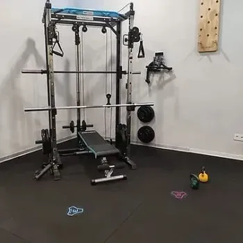 Un gimnasio con un banco, barras y pesas en el suelo.