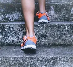 Una persona sube unas escaleras llevando zapatillas para correr.