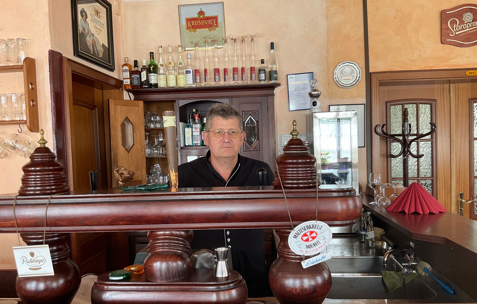 Der Inhaber steht in seinem Restaurant hinter der Bar.