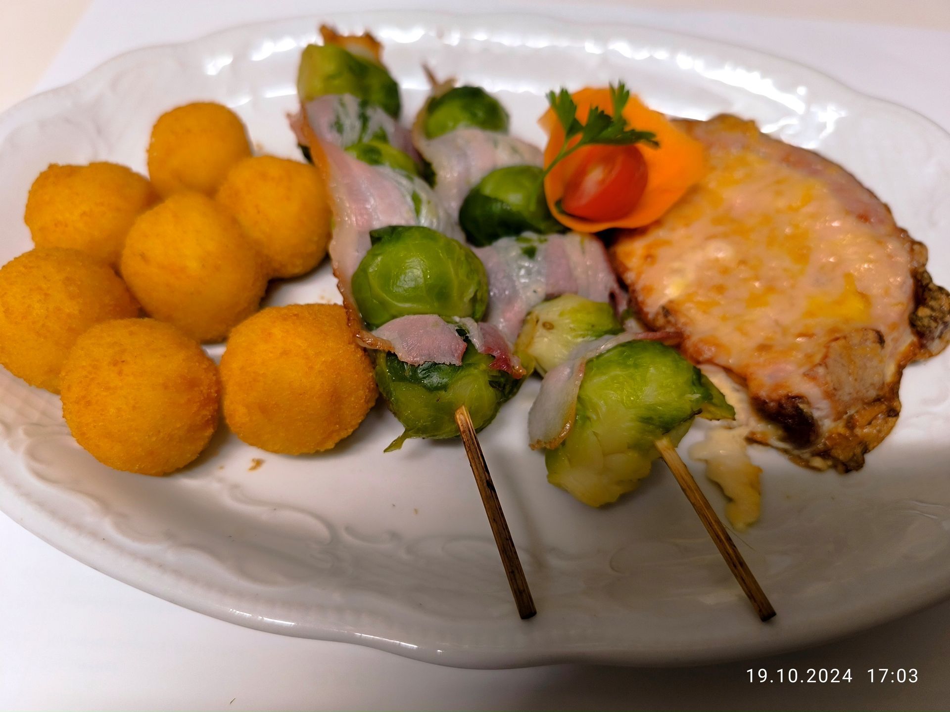 Ein weißer Teller mit Fleisch, Gemüse und Kartoffelbällchen