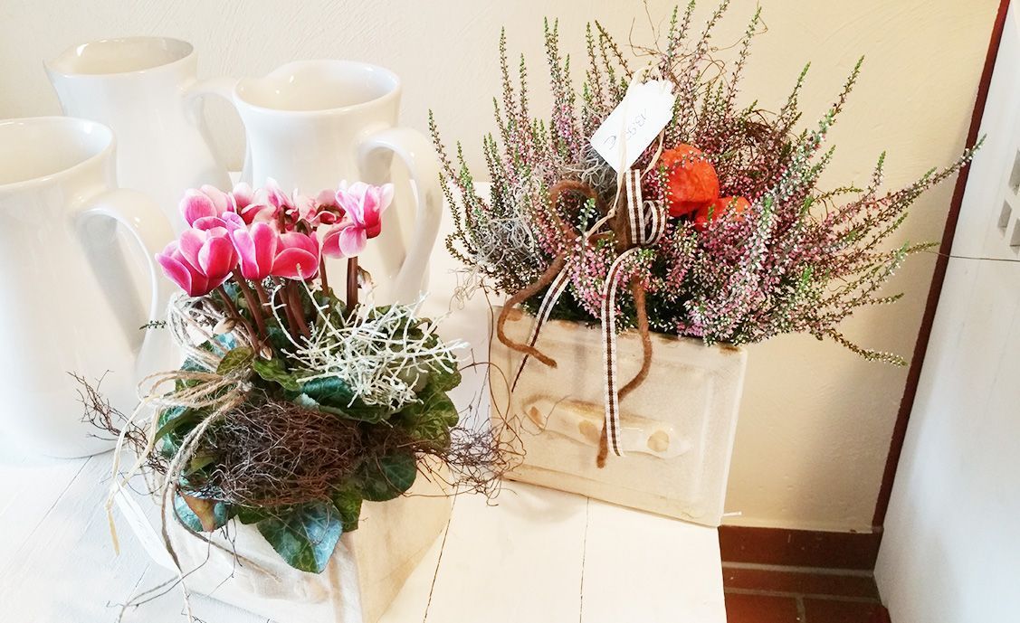 Blumen Liebe Woldegk - Zwei dekorative Blumengestecke auf einem weißen Tisch