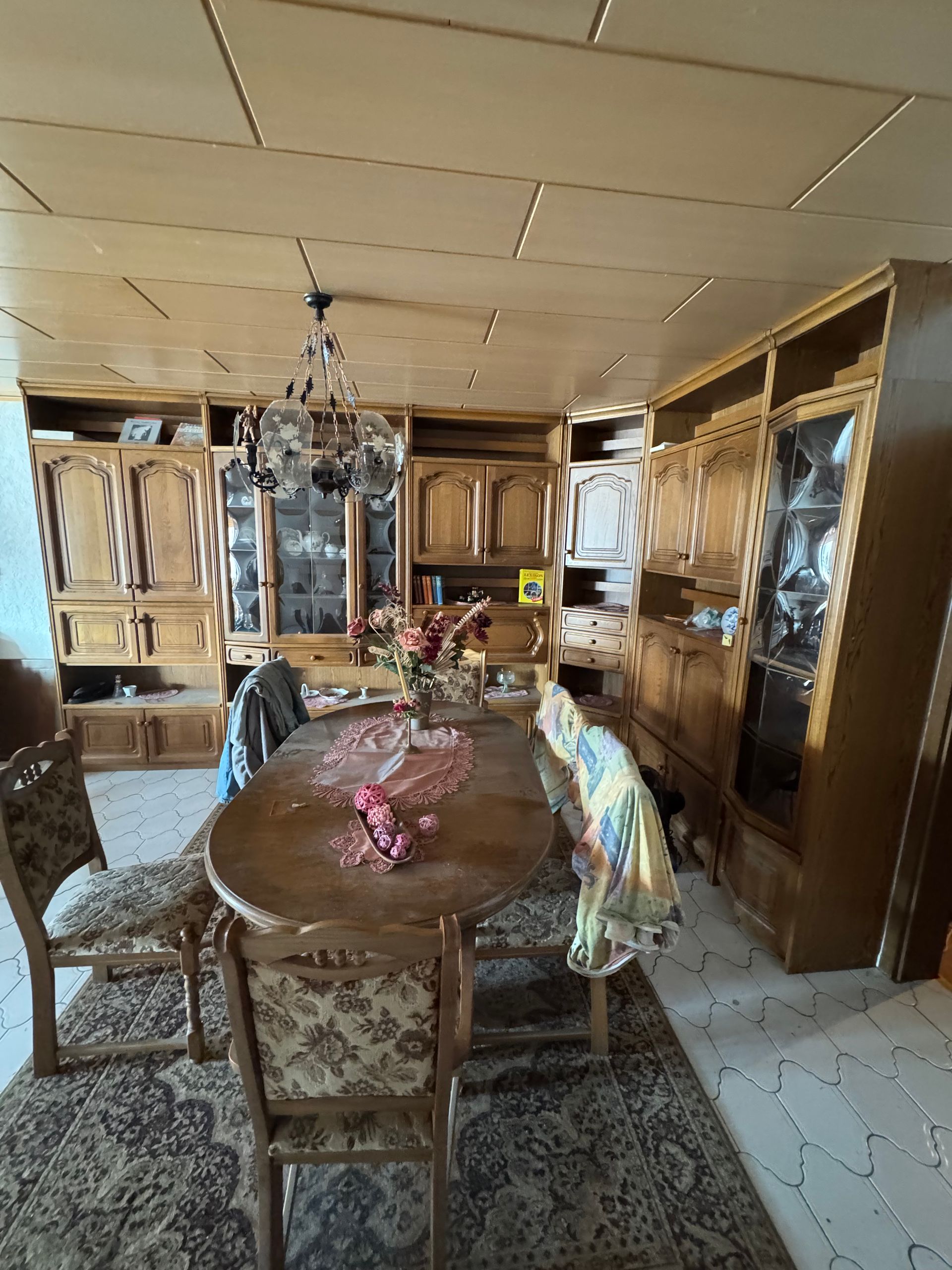 Esszimmer mit Holzmöbeln, ovalem Tisch, Stühlen, Kronleuchter und Einbauschränken.