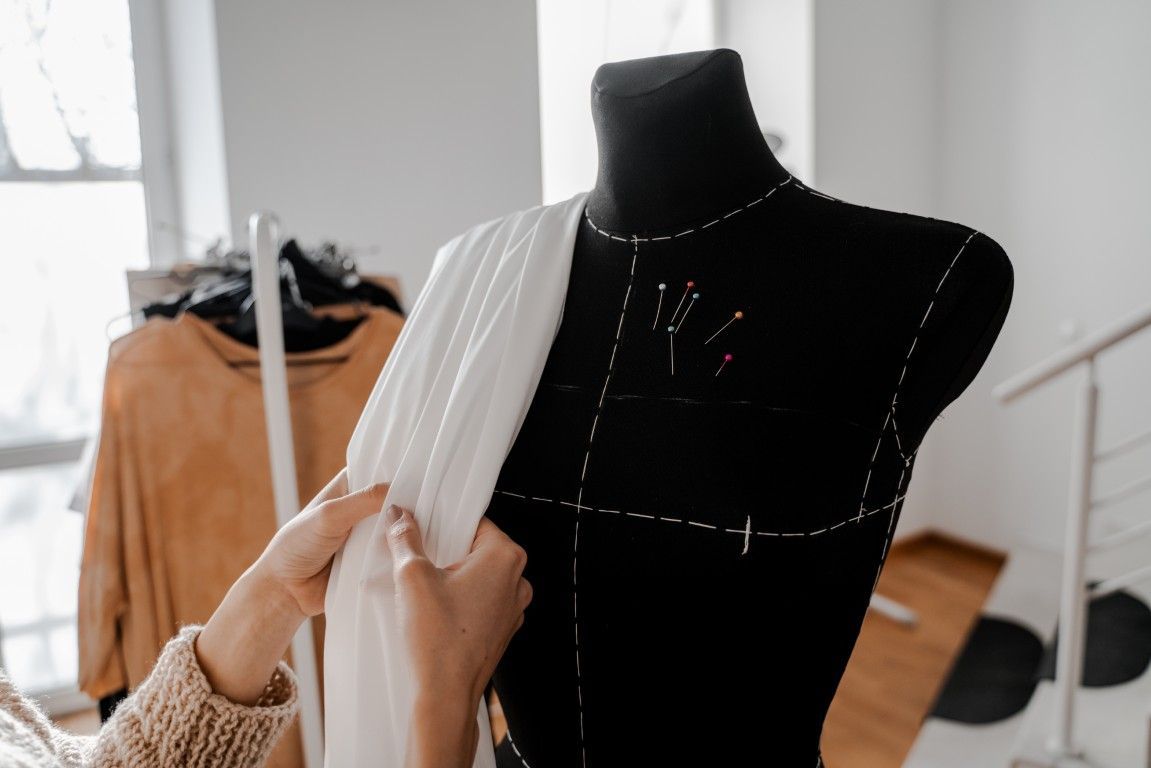 Ajuste de una prenda blanca sobre un maniquí negro en un taller de costura.