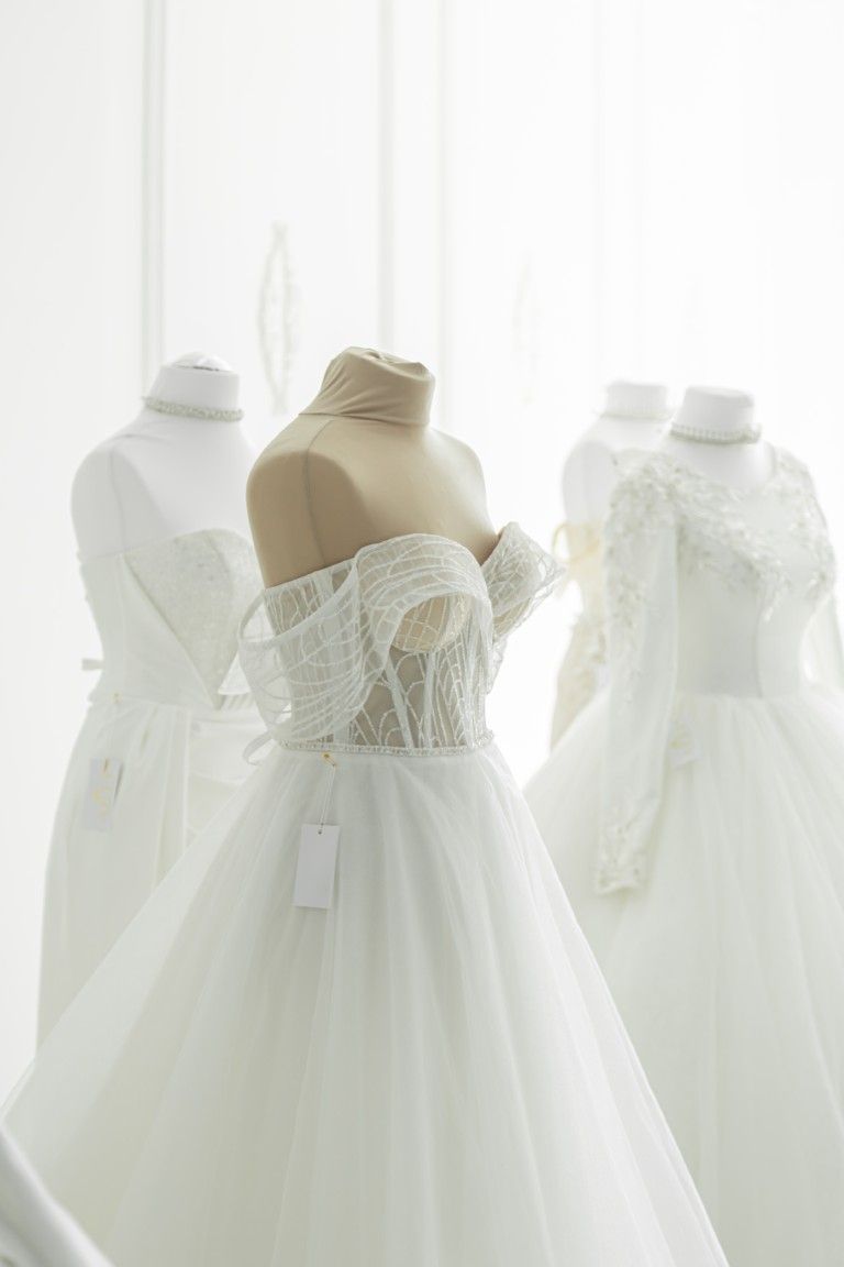 Vestidos de novia blancos expuestos en maniquíes en una luminosa boutique nupcial.