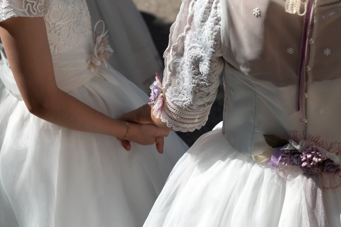 Dos niñas con vestidos blancos tomadas de la mano en un evento formal.