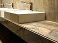 Baño moderno con lavabos rectangulares, grifería dorada y encimera de mármol.