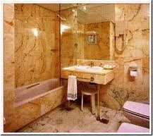 Un baño con paredes de mármol, bañera, lavabo e inodoro.