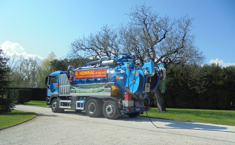 Un camion aspirateur bleu est garé sur le bord d'une route.