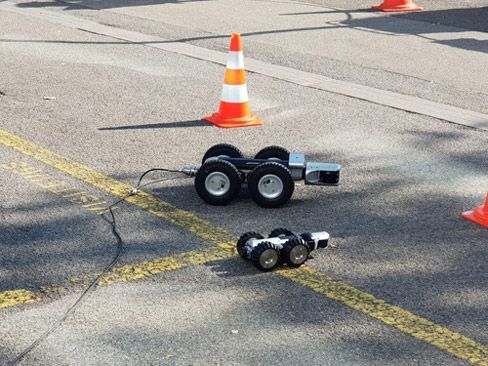 Une petite voiture est assise sur le bord de la route à côté d'un cône de signalisation.