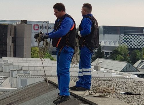 Deux hommes travaillent sur le toit d'un immeuble.