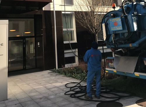 Un homme se tient à côté d'un camion aspirateur devant un bâtiment.