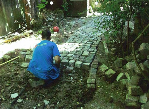 Un homme en chemise bleue est à genoux dans la terre