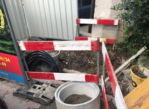 Un regard en béton est entouré d'une barrière rouge et blanche.