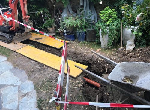 Une brouette est assise dans la terre à côté d'une petite excavatrice.