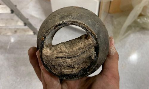 Une personne tient un morceau de métal dans sa main.