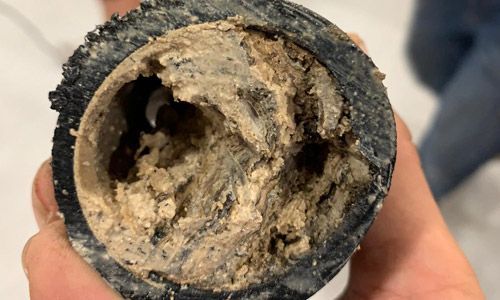 Une personne tient une pipe très sale dans sa main.