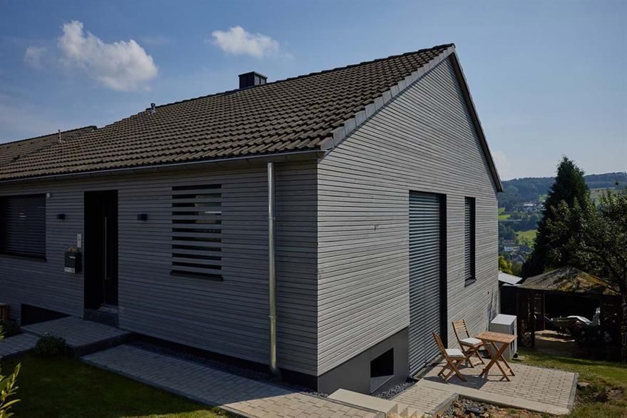 Ein kleines Haus mit einer Terrasse und einem Tisch und Stühlen davor.