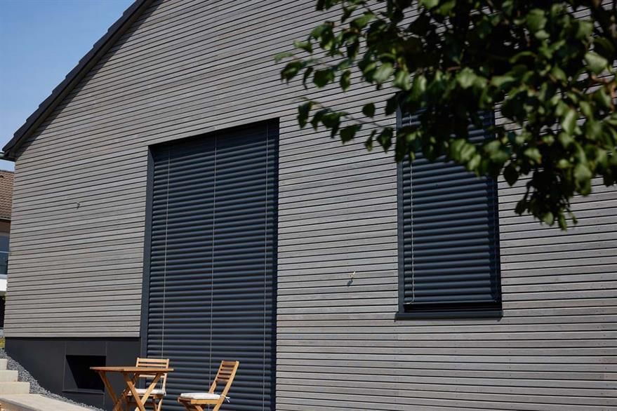 Ein Haus mit einem Tisch und Stühlen davor.