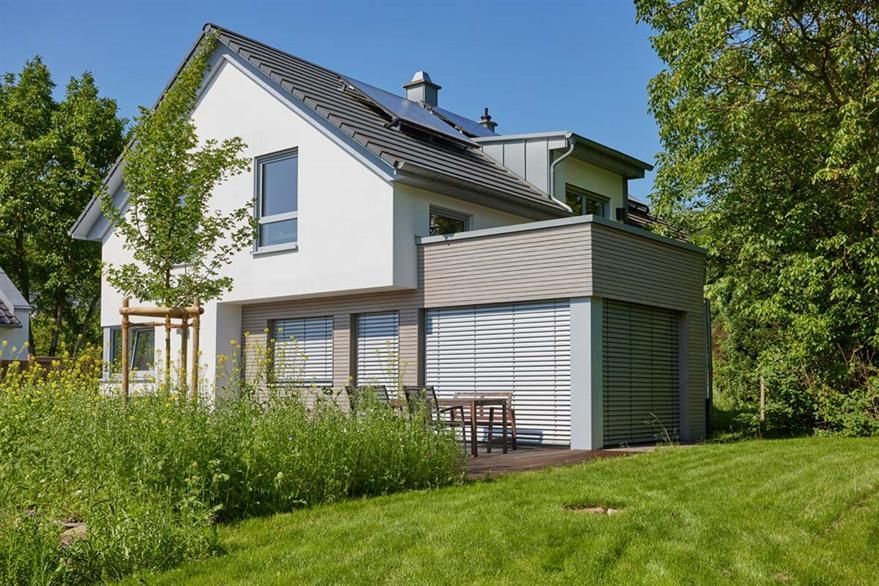 Ein weißes Haus mit einem Dach, auf dem sich Solarzellen befinden