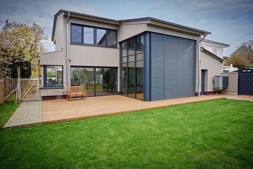 Ein großes Haus mit vielen Fenstern und einer großen Wiese davor.